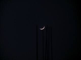 Golden Crescent Moon Against a Dark Minimalist Night Sky A delicate golden crescent moon glowing in a dark night sky, framed by subtle vertical silhouettes, creating a peaceful and minimalist celestia © Farr.rmdn