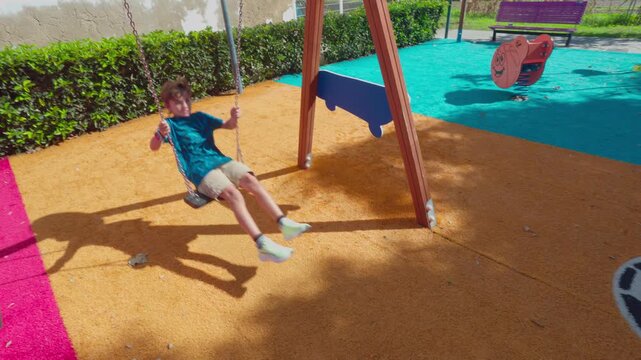 Young Boy Swinging on a Playground Swing Outdoors