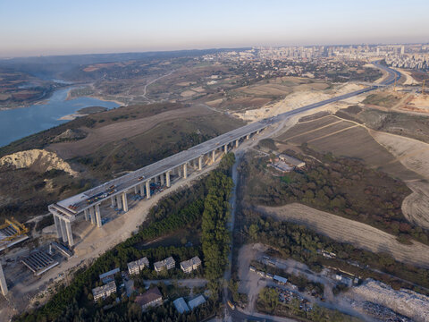 Aerial view of a bridge construction site with concrete pillars and elevated highway, near a reservoir and rolling hills in Istanbul, Istanbul, Turkiye.