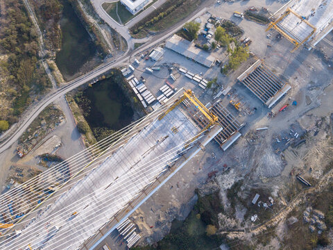 Aerial view of a cable-stayed bridge under construction with concrete segments, steel cables, and heavy machinery on the surrounding site in Istanbul, Istanbul, Turkiye.