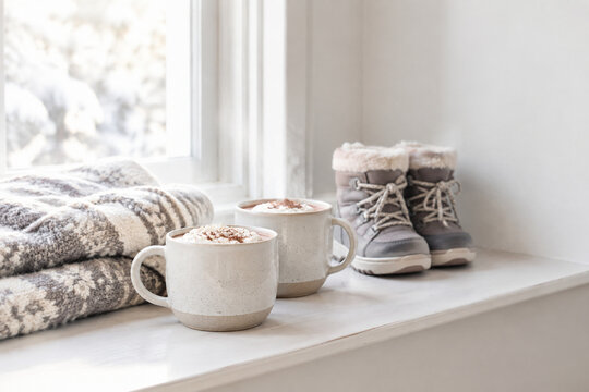 Winter break family activities with hot cocoa, blanket and snow boots on window ledge