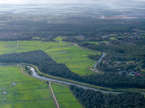 River winds through lush green fields. Villages dot the distant, hazy horizon at Kubang Semang