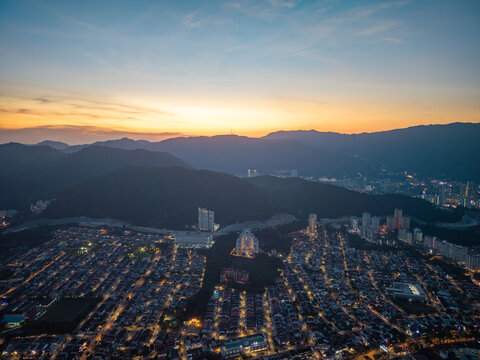 Sunset paints sky in soft gold and blue. City lights twinkle across winding streets at Jelutong,Penang