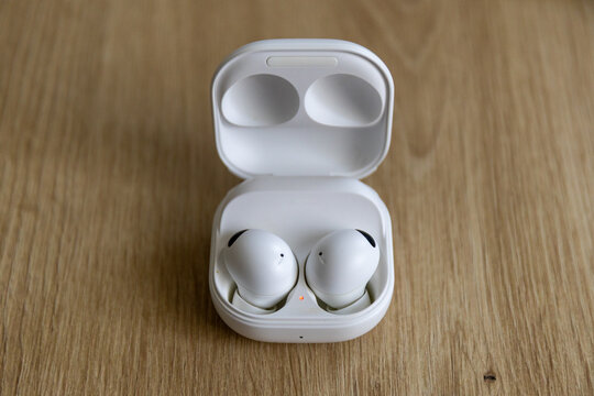 Close-up of true wireless Bluetooth earbuds on a wooden table background