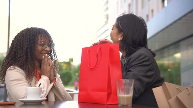 young friends exchanging presents outdoors during christmas time, diverse female friends celebrating a special occasion. The joy of giving and friendship concept