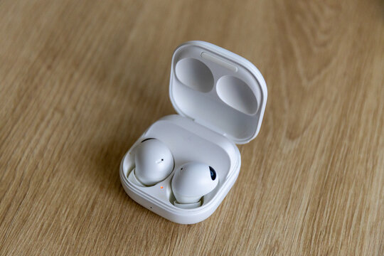 Close-up of true wireless Bluetooth earbuds on a wooden table background
