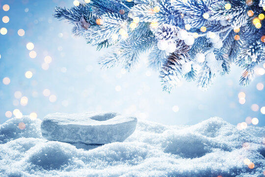 Frosty pine branch and snowy stone as podium on abstract winter snow background