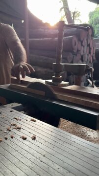 Horizontal side view of carpenter cutting wood on table circular saw in rustic workshop