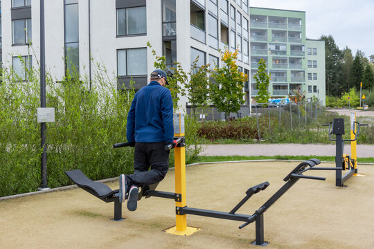 A man is exercising on an outdoor Parallel Bars or Dip Station in a public place in Finland on an autumn day