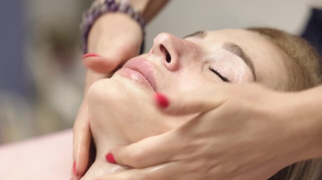 Close up of beautician hands massaging a woman's face. Professional facial treatment for mature skin care, relaxation and improved skin appearance.