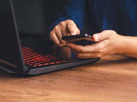 Person using smartphone beside laptop for communication
