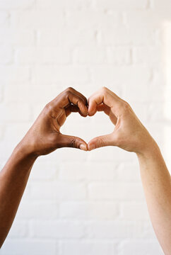 Diverse hands forming a heart shape against a white background  
