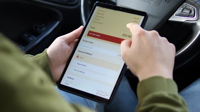 Shopper reviews an online grocery cart with sale prices, savings, promo code and payment options on a tablet, reflecting digital retail and cost-conscious shopping.