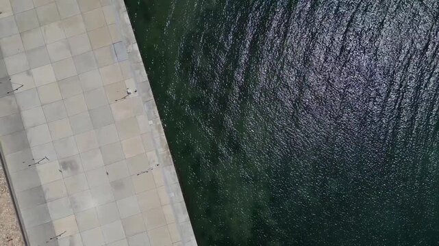 Aerial Top Down View of Concrete Pier Promenade and Dark Sea Water Surface