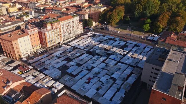 Aerial drone view of Piazza dell'Otto Agosto in Bologna, Italy, filled with market stalls and surrounded by historic buildings in the city center.