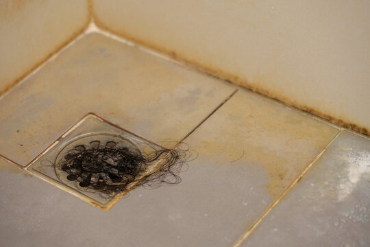 bathroom with a toilet. dirty joints between the tiles, toxic black mold in the corner. Clogged and dirty sewer pipes floor drain.	
