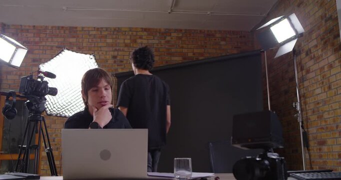 Diverse male crew handing papers, moving to camera, and seated editor typing laptop preparing shoot