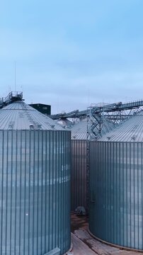 Flying closer to the tanks for processing and storing wheat grain. Modern agricultural enterprise. Grain business concept. Vertical video