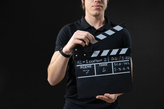 Male slate operator holding slate, lifting hinged top in studio wearing black polo with wristwatch