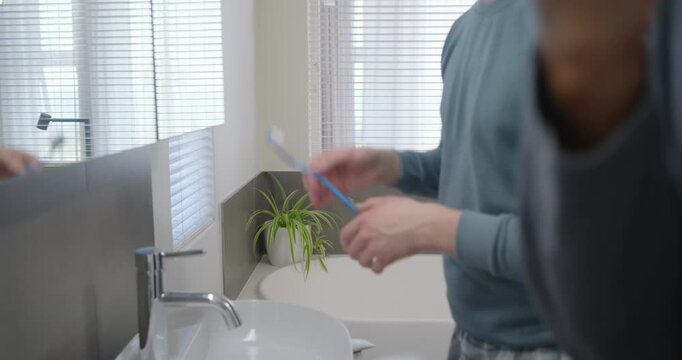 African American men pressing paste on brush, rubbing cream at bathroom mirror for morning