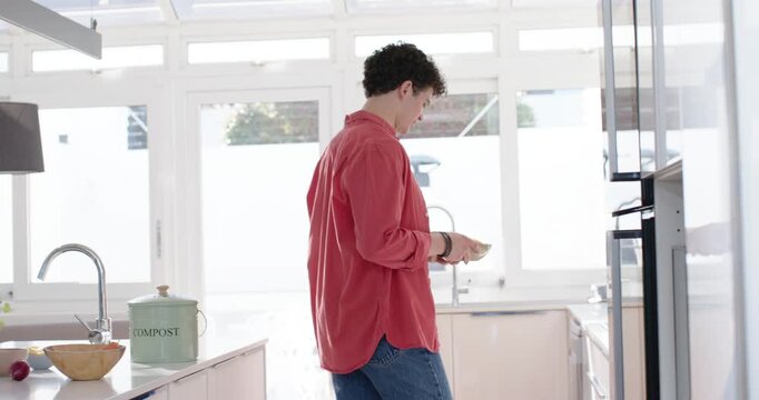 Male friends redshirted man moving rolls to oven after talking, warming bread in kitchen