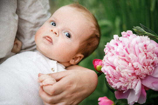 Happy Mothers day! Cute newborn baby in mother hands close up among flowers in the garden. Love, care and family in countryside concept.  Adoption and maternity
