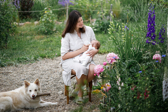 Happy Mothers day! Mother hugging and feeding cute newborn baby  with bottle in the garden. Love, care and family in countryside concept. Adoption and maternity