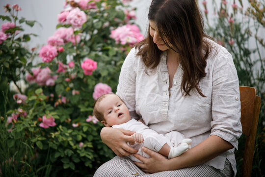 Happy Mothers day! Mother hugging cute newborn baby among flowers in the garden. Love, care and family in countryside concept. Adoption and maternity