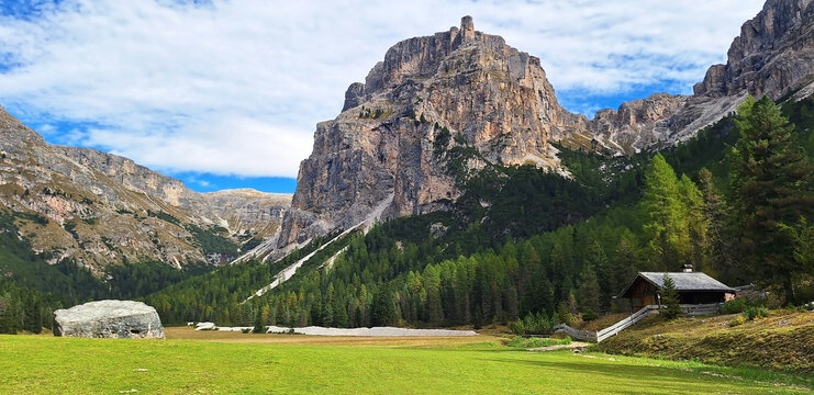 The winding Vallunga hiking trail among the rocks with a mountain refuge in the Puez Geisler nature park in Selva. Panorama.