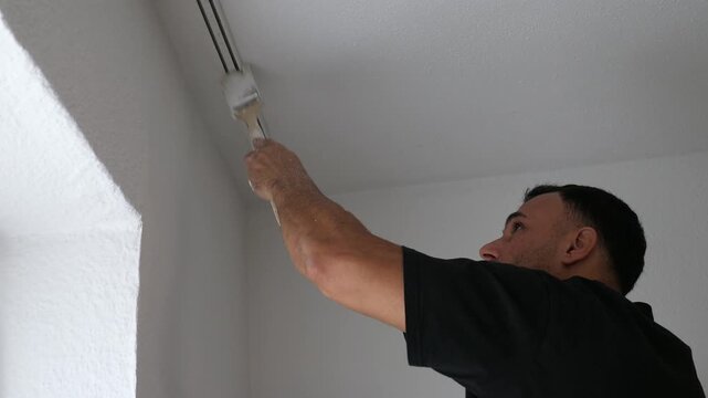 Close Up of Painter Painting Ceiling Edge and Curtain Track White with Small Brush Precision Detail Work Home Renovation DIY Project Concept Indoors