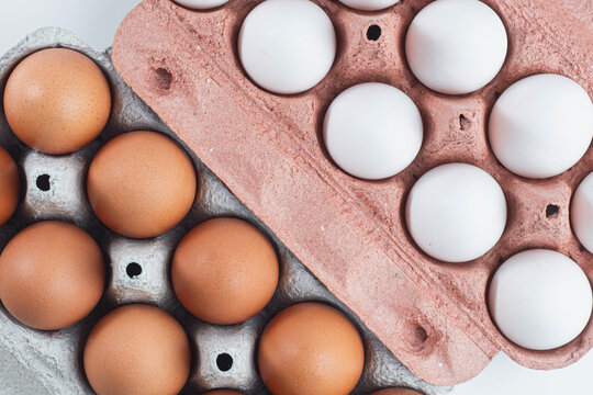 Top view of brown and white chicken eggs in paper cartons. Fresh organic farm eggs, grocery staple, poultry farming, protein source, cooking preparation and food market concept.