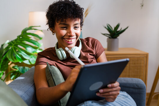 African American woman smiling using tablet with stylus pen
