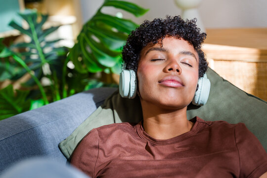 African American woman relaxing on couch with headphones and indoor