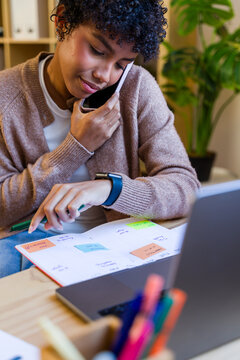 African American woman making a phone call and checking calendar