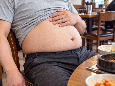 Man touching his bloated stomach after overeating at a restaurant