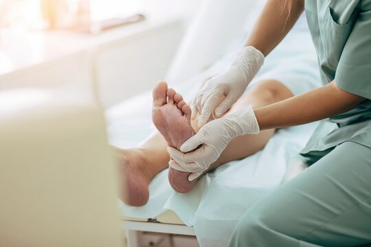 Podiatrist examining the sole of a patient&rsquo;s foot with white gloves