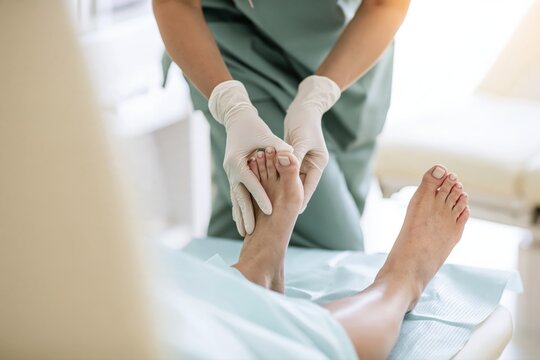 Podiatrist assessing a patient&rsquo;s foot and toes on an examination couch