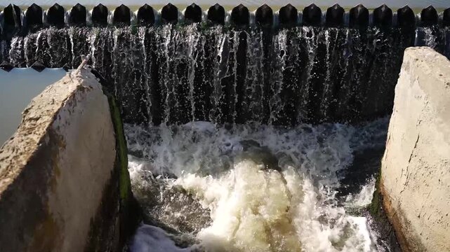 Water cascading over concrete weir with white foam