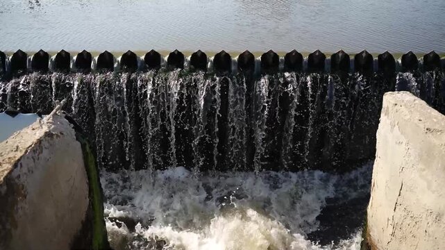 Water flowing over concrete weir into river