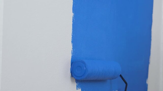 Roller Brush Painting, Worker painting on surface wall Painting apartment, renovating with blue color paint. Leave empty copy space white to write descriptive text beside.
