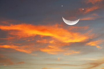 Beautiful sunset sky with crescent moon and bright star over colorful clouds © darkfoxelixir
