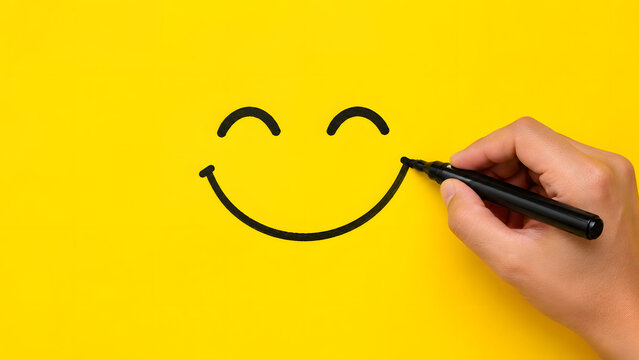Hand drawing a black smiley face on a bright yellow background for
