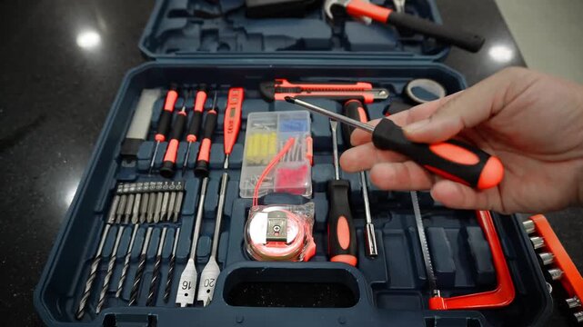 Hand technician in work holding an screwdriver. Video. Macro close-up hand man holds an screwdriver and, with a tool box in the background. Man with screwdriver. Shot of tools, anvil.