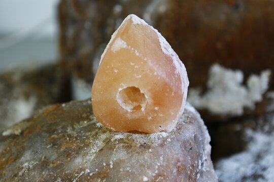 A pink rock salt crystal with a drilled hole rests peacefully.