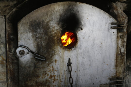 Flames blaze through the observation hole of a traditional brick furnace.