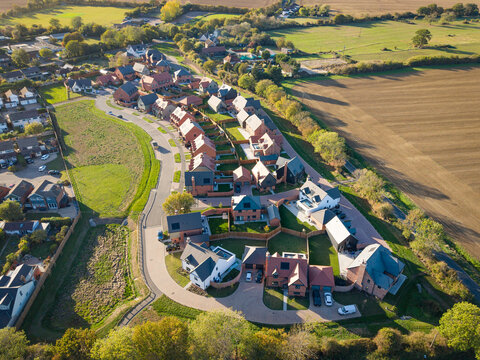 Drone view of a newly completed housing development of detached and semi-detached homes in the rural Essex village of Blackmore, UK. On the left is the older part of the village.