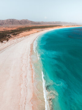Aerial view of Aomak Camping Site featuring a pristine white sand beach, turquoise waters, and arid coastal landscape in Hadibu, Socotra, Yemen.
