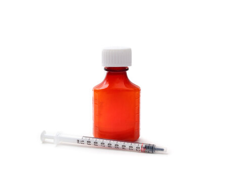 Isolated oral medication bottle with dosing syringe. Liquid anti-inflammatory or steroid for pets or children, dispensed by owner or parent. Dosage line visible. Selective focus.
