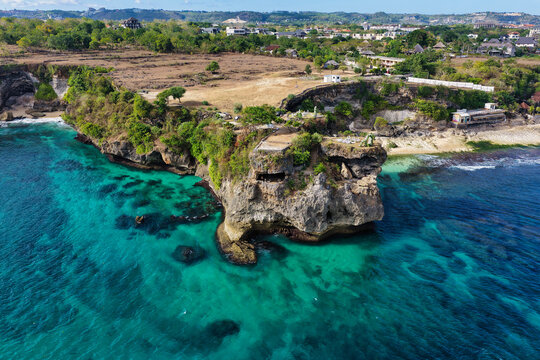 Aerial view of Balangan Beach featuring turquoise waters, rugged rocky cliffs, and lush coastal vegetation in South Kuta, Bali, Indonesia.