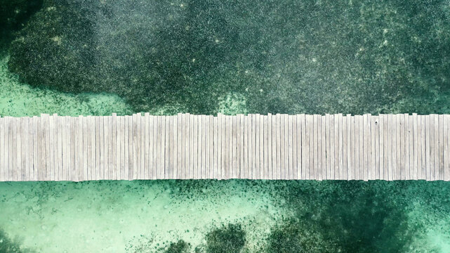 Aerial view of wooden boardwalk across patterned shallows in Mexico